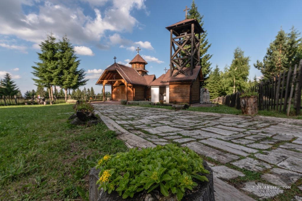 Wooden chapel on a green hill under a blue sky