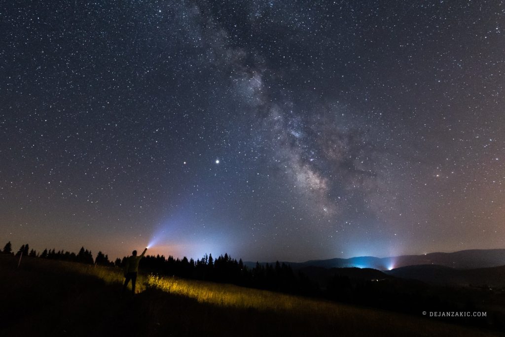 Milky Way over a valley with distant lights