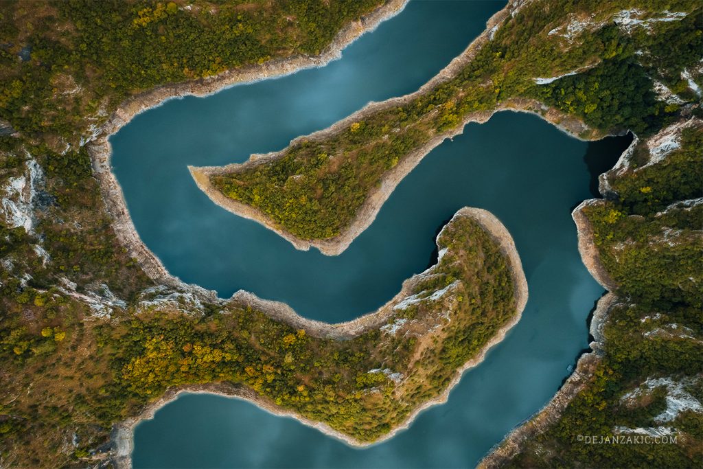 Aerial view of a winding turquoise river through a forested canyon